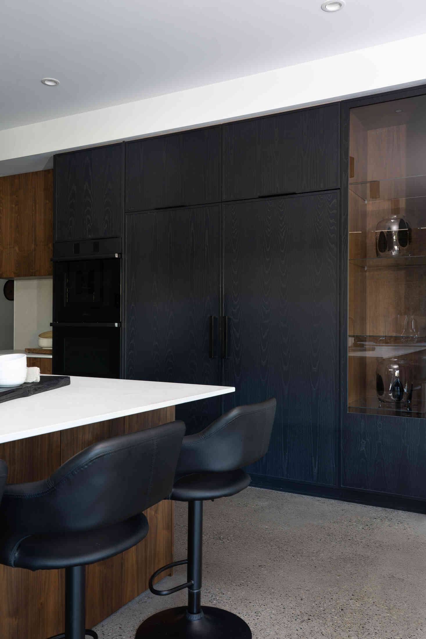 Stained black ash cabinetry in kitchen with panel-ready fridge freezer